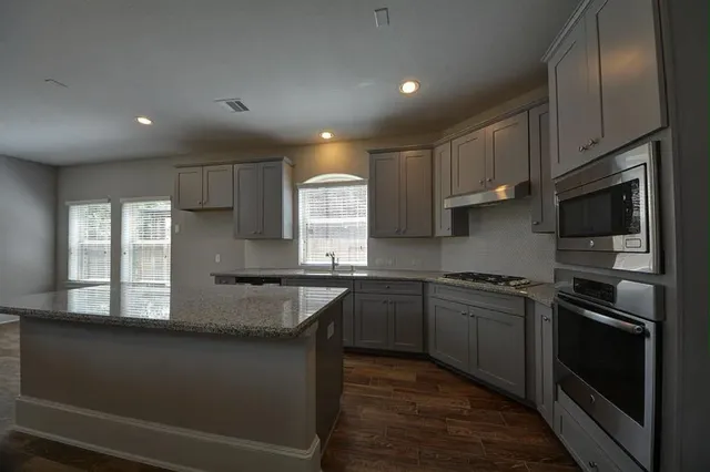 a kitchen with stainless steel appliances granite countertop stove a sink and a microwave