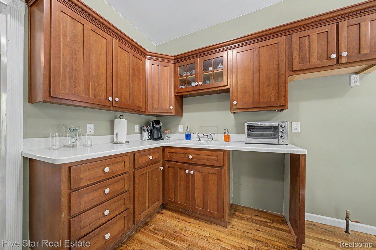 175 Bishop Road Sterling, MI 48659 - Photo 16 of 41 Kitchenette featuring extensive wood cabinetry with white knob hardware, white countertops, and wood-finish flooring