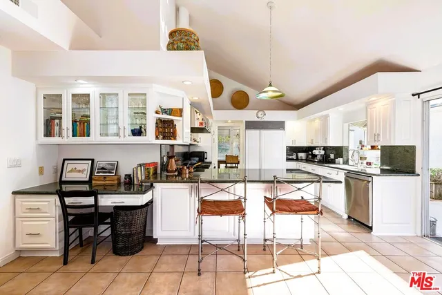 a kitchen with stainless steel appliances kitchen island granite countertop a stove a sink a dining table and chairs with the cabinets