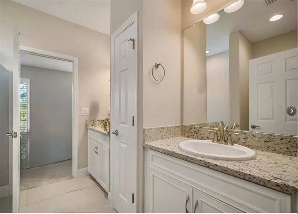 7004 Mainland Avenue Apollo Beach, FL 33572 - Photo 56 of 67 a bathroom with a granite countertop sink a mirror and a shower
