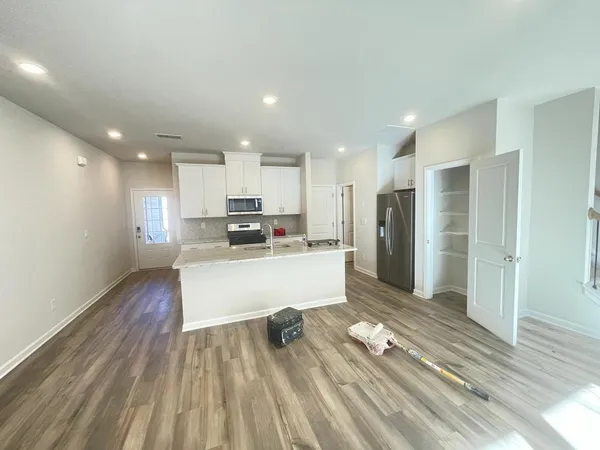 a view of kitchen with kitchen island wooden floor center island and stainless steel appliances