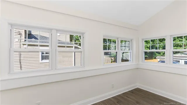 a view of an empty room with wooden floor and windows