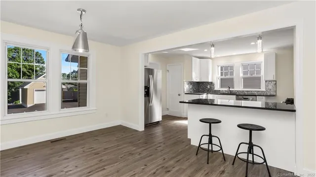a kitchen with stainless steel appliances granite countertop a kitchen island hardwood floor and a sink