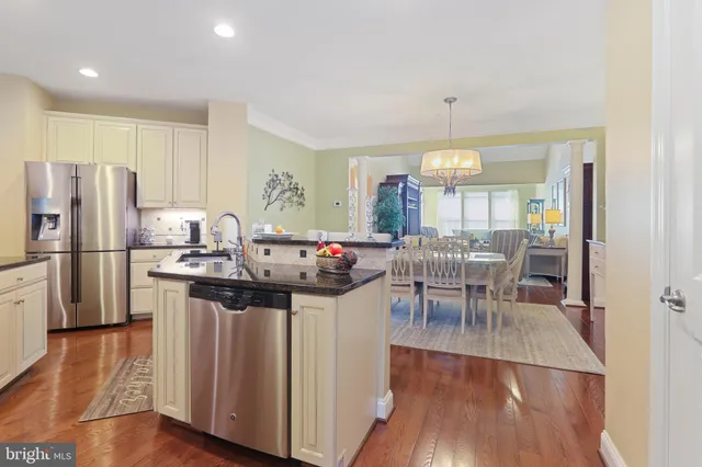 a kitchen with stainless steel appliances granite countertop a refrigerator a stove and a wooden floors