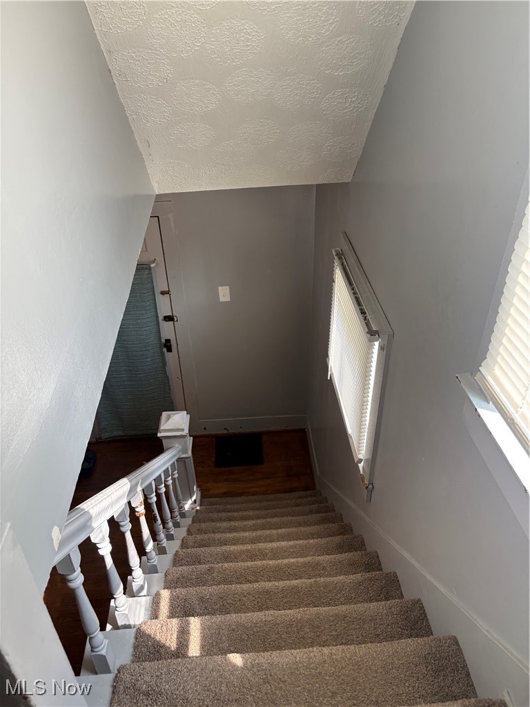 11 Front Street Rittman, OH 44270 - Photo 25 of 31 Stairway featuring a textured ceiling, wood finished floors, and vaulted ceiling