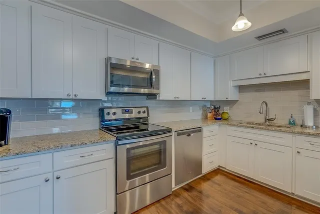 a kitchen with stainless steel appliances granite countertop a refrigerator a stove and a sink