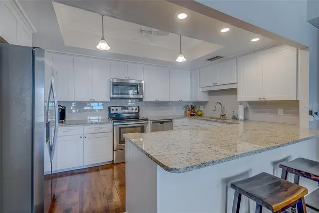 a kitchen with a sink a center island stainless steel appliances and cabinets