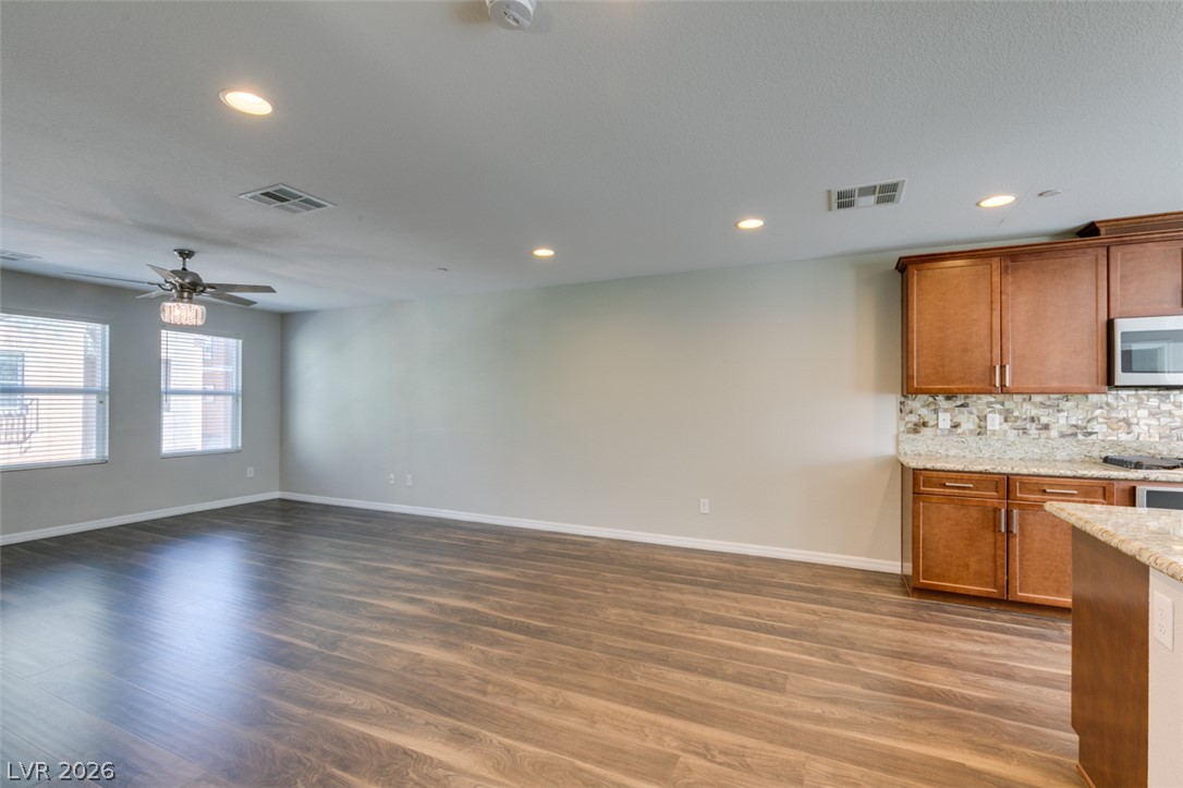4650 Ranch House Road, Unit 46 North Las Vegas, NV 89031 - Photo 7 of 38 Rich wood-look flooring stretches across an open living area adjacent to a built-in kitchen.