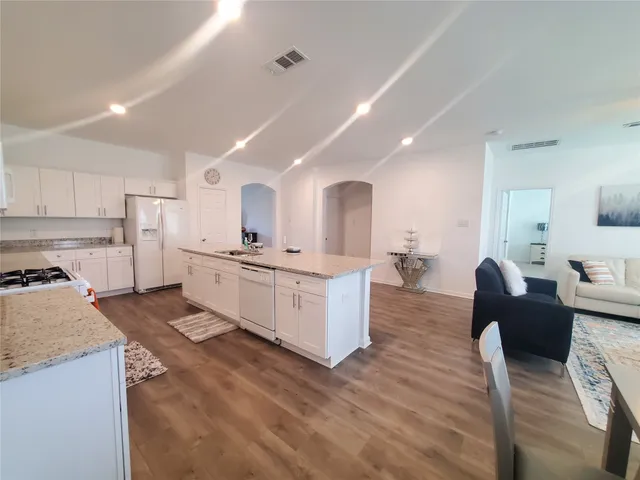a large white kitchen with cabinets a sink a window and stainless steel appliances