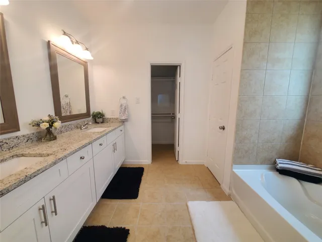 a spacious bathroom with a granite countertop sink and a mirror