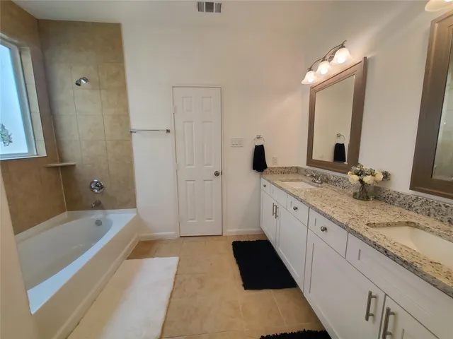 a spacious bathroom with a granite countertop tub sink and mirror