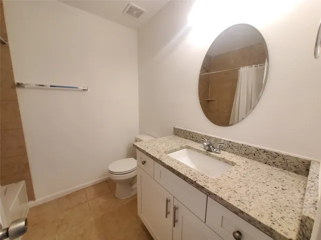a bathroom with a granite countertop sink a toilet and a mirror