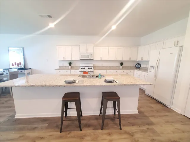 a kitchen with stainless steel appliances granite countertop a table chairs sink refrigerator and cabinets