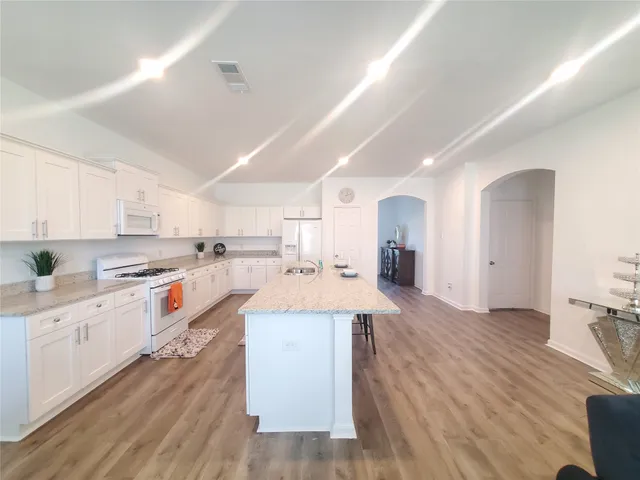 a large kitchen with granite countertop a large counter top a sink stainless steel appliances and cabinets