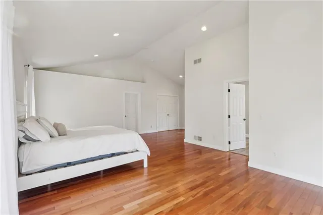 a spacious bedroom with a bed and a wooden floor