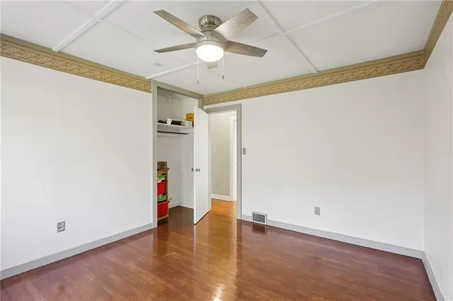 an empty room with wooden floor and ceiling fan