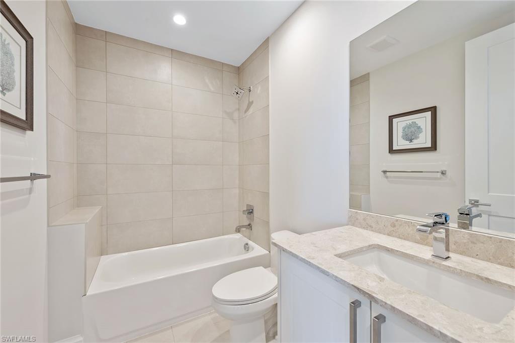 1111 Central Avenue, Unit 506 Naples, FL 34102 - Photo 13 of 21 a bathroom with a granite countertop sink a toilet a mirror a bathtub and shower
