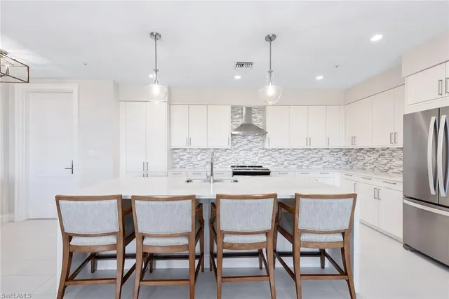 a kitchen with stainless steel appliances kitchen island granite countertop a dining table chairs and white cabinets