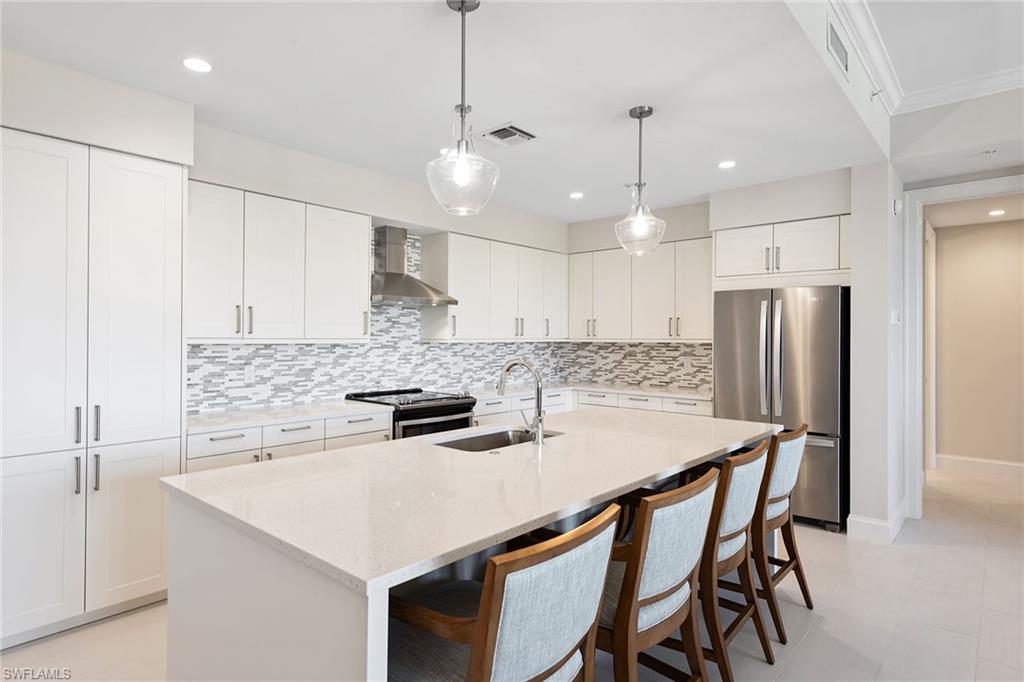 1111 Central Avenue, Unit 506 Naples, FL 34102 - Photo 7 of 21 a kitchen with stainless steel appliances granite countertop a sink a stove a refrigerator and white cabinets with wooden floor
