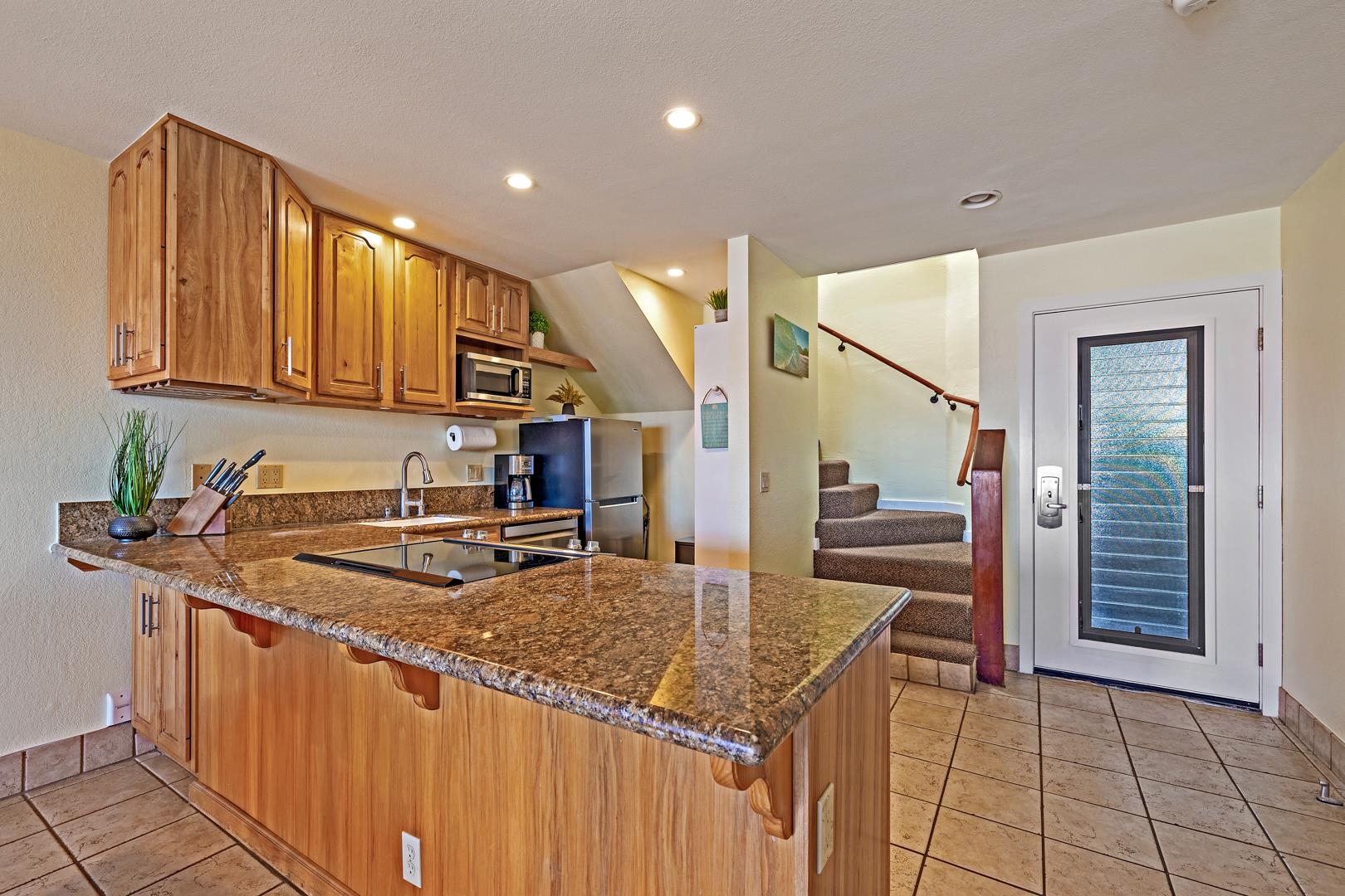 4909 Lower Honoapiilani Road, Unit E5 Lahaina, HI 96761 - Photo 16 of 28 a kitchen with kitchen island granite countertop a sink stove and cabinets