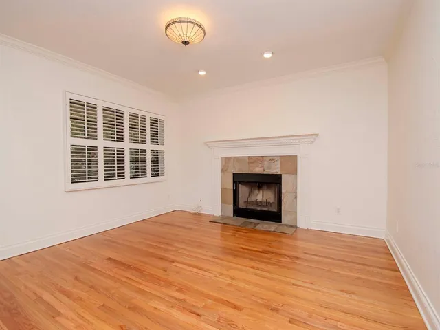 a view of empty room with wooden floor and fireplace