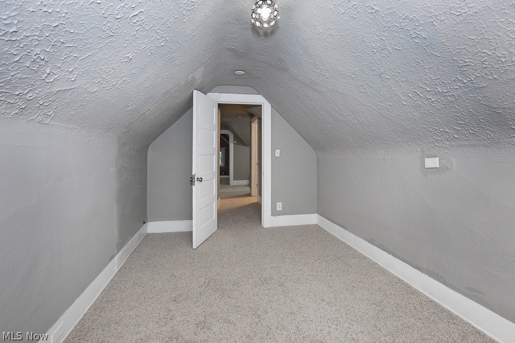 1892 Beersford Road Cleveland, OH 44112 - Photo 33 of 47 Additional living space featuring vaulted ceiling, carpet, and a textured ceiling