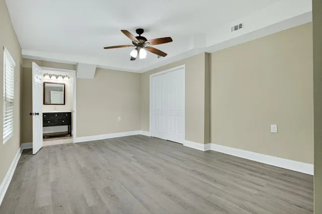 an empty room with wooden floor closet and windows