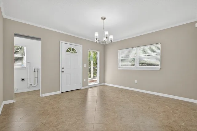 an empty room with chandelier fan and windows