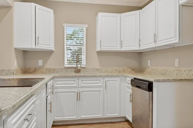 a kitchen with granite countertop white cabinets and a sink
