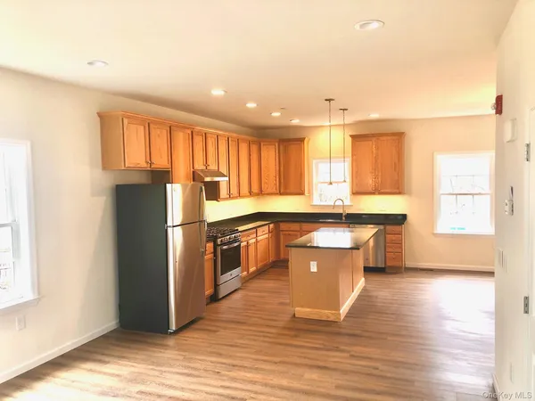 a kitchen with stainless steel appliances granite countertop a refrigerator a sink dishwasher a stove and a refrigerator with wooden floor