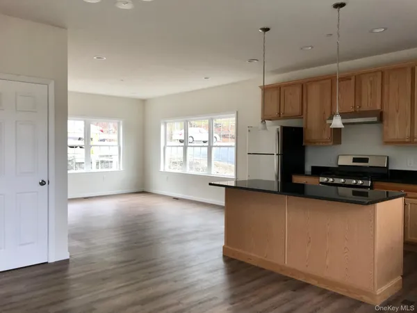 a kitchen with granite countertop a stove a sink a refrigerator and a window