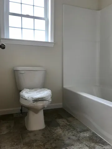 a white toilet sitting next to a window