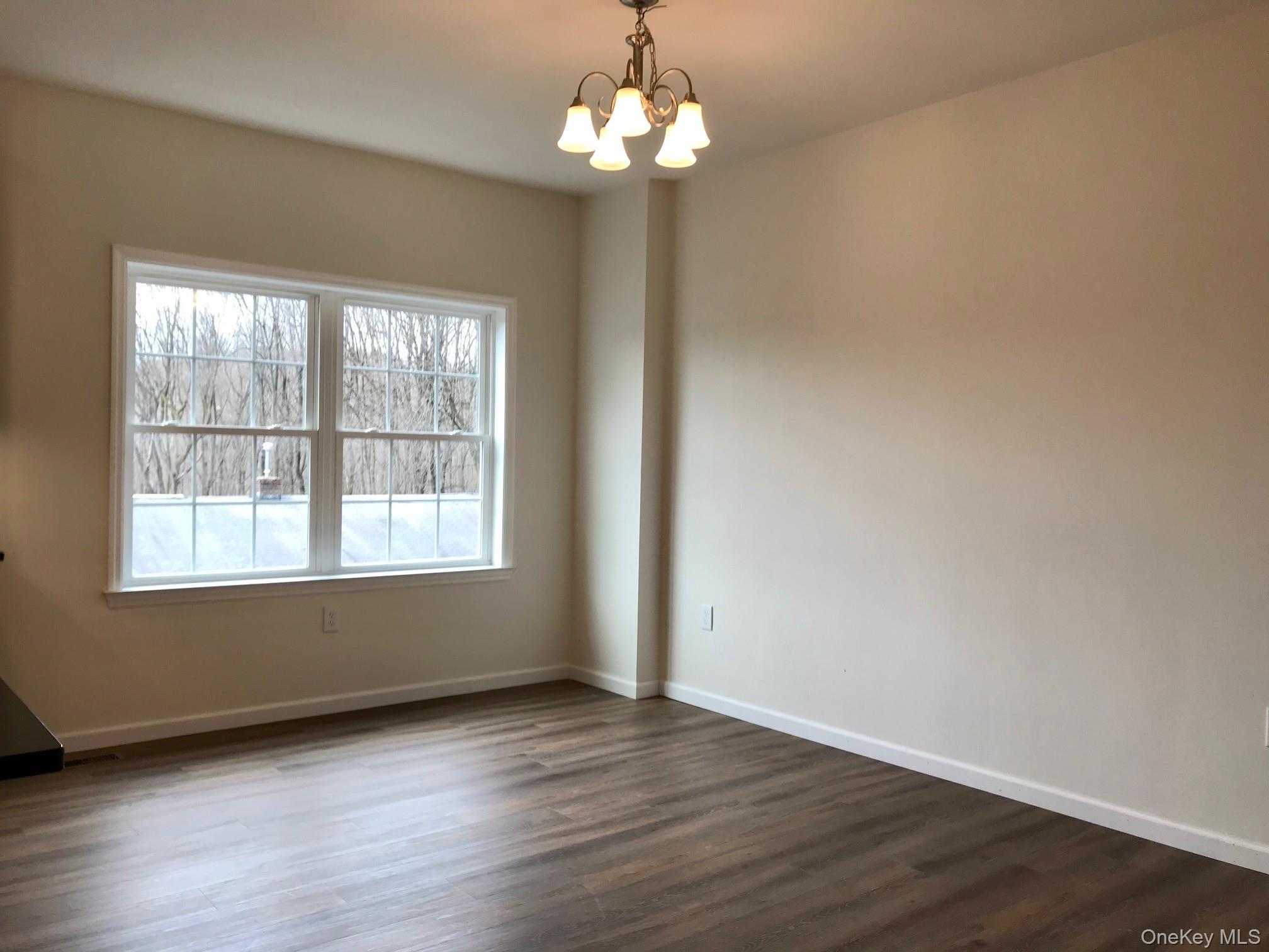 1004 North Division Street, Unit B Peekskill, NY 10566 - Photo 4 of 17 Unfurnished room featuring dark wood finished floors and a chandelier