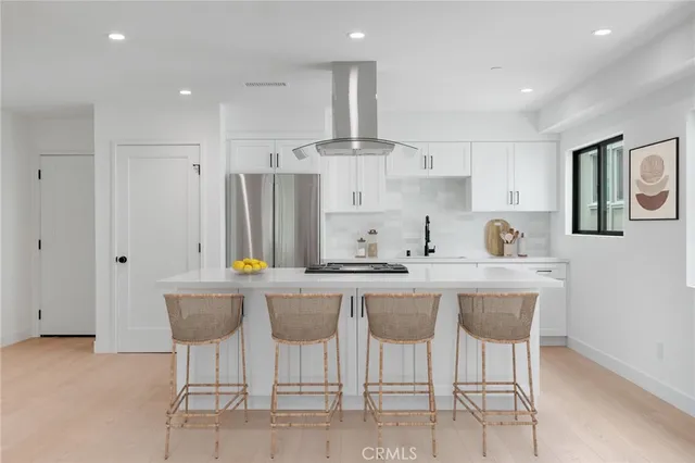 a kitchen with stainless steel appliances a table chairs refrigerator and cabinets