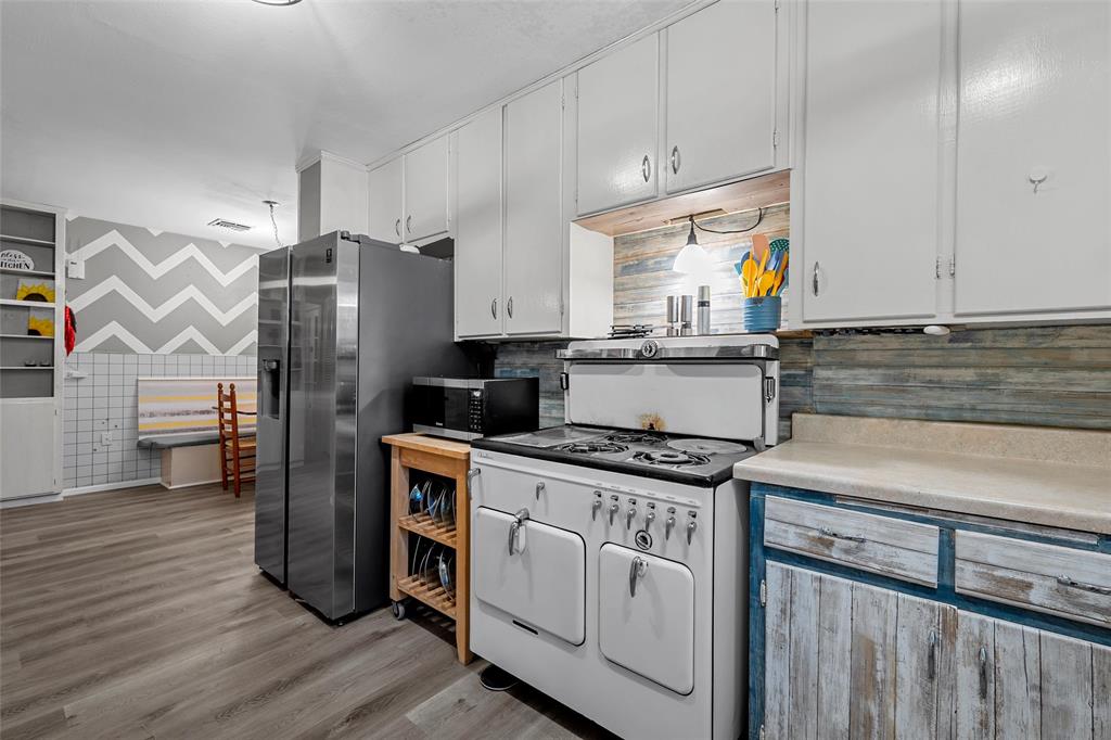 301 North 40th Street Waco, TX 76710 - Photo 12 of 26 Galley kitchen featuring a vintage-style white range, stainless steel refrigerator, white upper cabinetry, and wood-finish flooring