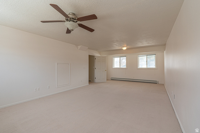 1045 Fox Farm Road Logan, UT 84321 - Photo 47 of 65 Empty room featuring light colored carpet, a baseboard radiator, a textured ceiling, and a ceiling fan