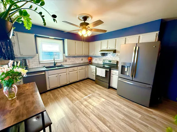 a kitchen with stainless steel appliances granite countertop a sink refrigerator and cabinets