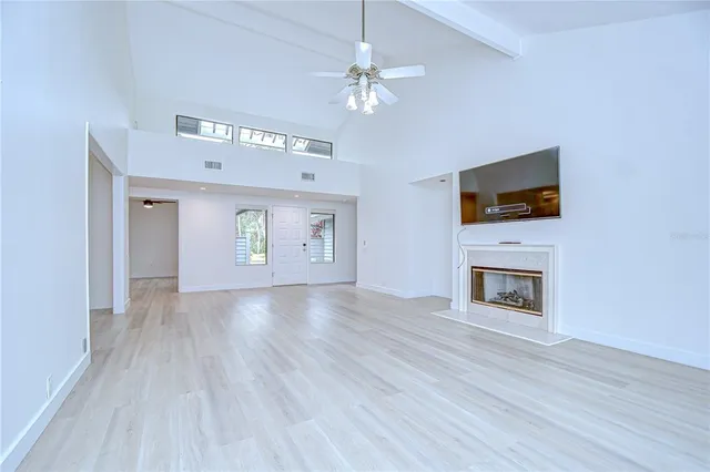 an empty room with wooden floor ceiling fan and windows