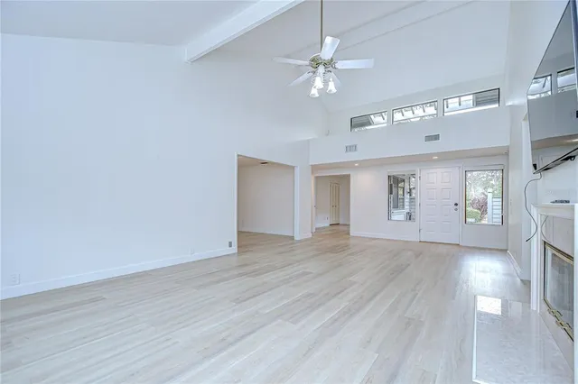 an empty room with wooden floor and a ceiling fan