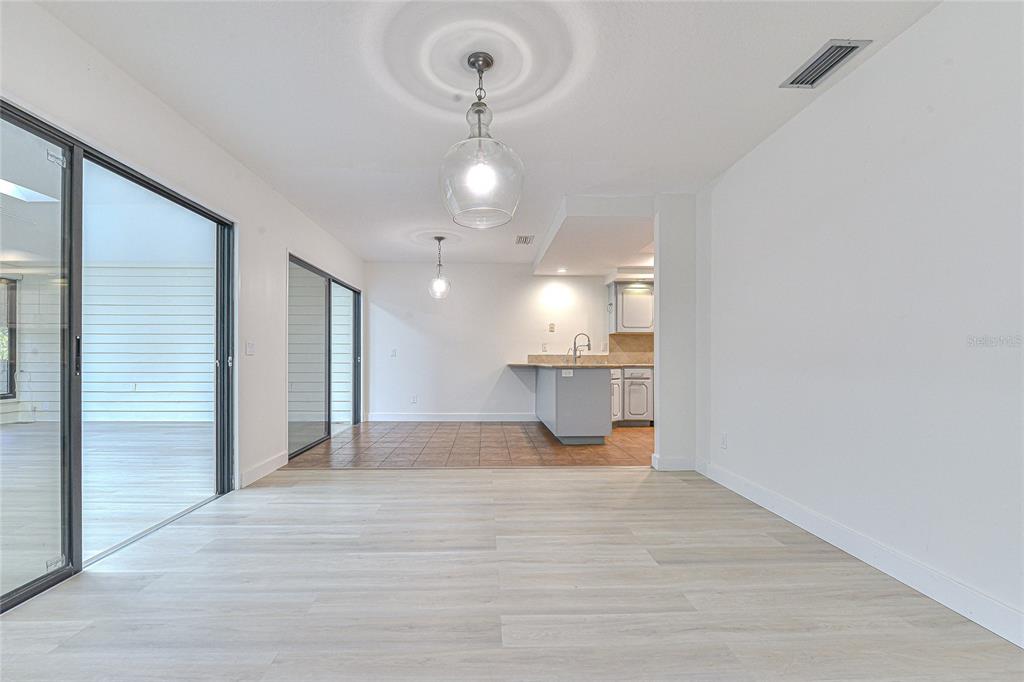 5355 Cobblestone Court Wesley Chapel, FL 33543 - Photo 23 of 59 a view of empty room with wooden floor and kitchen view