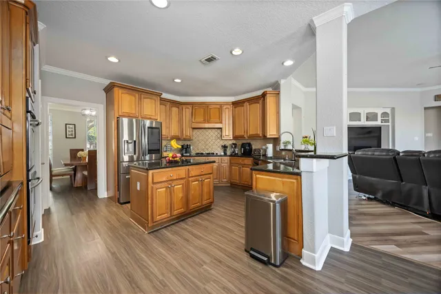 a kitchen with stainless steel appliances granite countertop wooden floors a stove a sink and a refrigerator