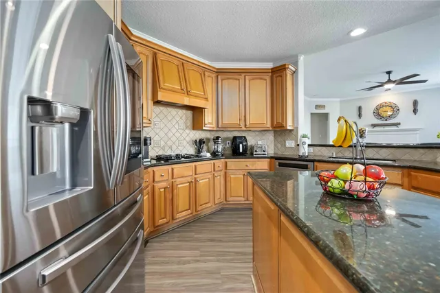 a kitchen with stainless steel appliances granite countertop a sink a stove and a refrigerator