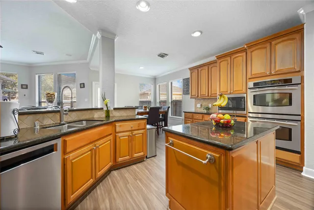 a kitchen with stainless steel appliances granite countertop a stove top oven a sink dishwasher a refrigerator and cabinets with wooden floor