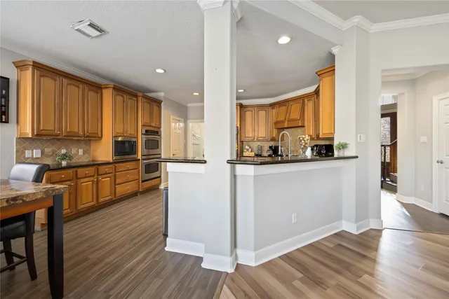 a kitchen with stainless steel appliances granite countertop a refrigerator a stove and a wooden cabinets with wooden floor