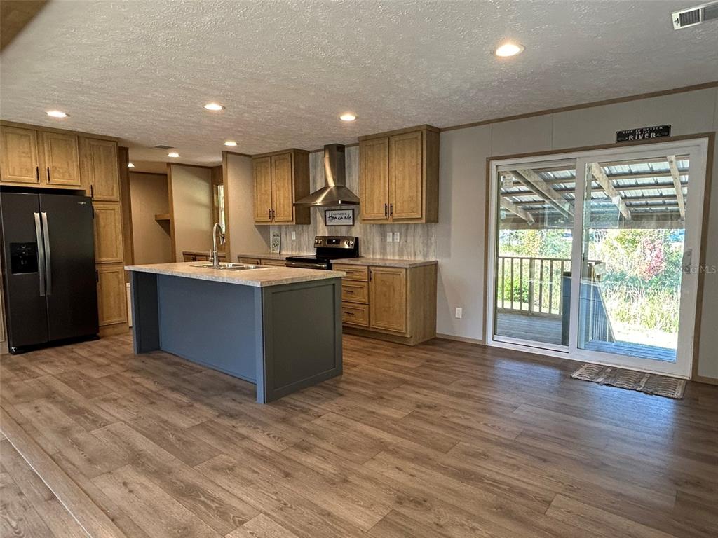 6443 Finance Avenue Weeki Wachee, FL 34607 - Photo 14 of 45 a kitchen with stainless steel appliances granite countertop a refrigerator a sink dishwasher a stove and a refrigerator with wooden floor