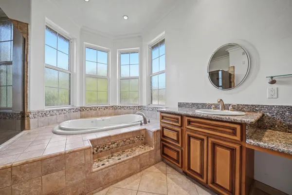 a spacious bathroom with a granite countertop tub a sink and a large mirror
