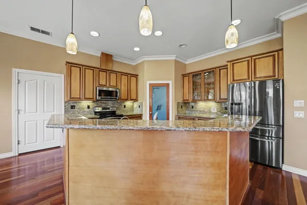 a large kitchen with stainless steel appliances granite countertop a refrigerator a stove top oven a sink dishwasher and wooden cabinets