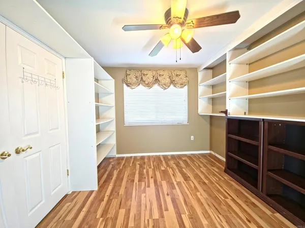 a view of empty room with wooden floor and fan