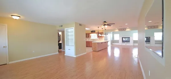 a view of a big room with wooden floor and a kitchen