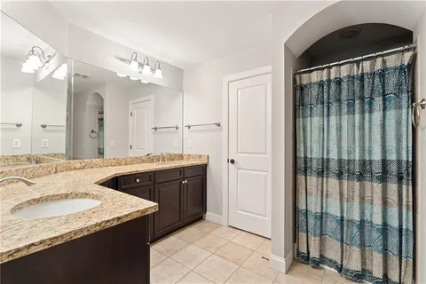 a spacious bathroom with a granite countertop sink a mirror and shower